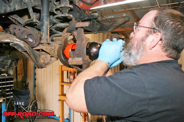 On some axles the orange grease cup can be installed on the axle shaft before it is inserted. On others, it must be in place before the shaft is inserted into the housing. RCVs distinctive orange grease cup tells everyone that your front axles have a lifetime warranty. Kevin Lakeat whose shop all this work was doneis slipping the axle into the housing carefully so that the splines arent damaged. The shaft may have to be jockeyed back forth so the splines will mate with the gears.